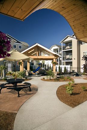 Tumwater apartment for rent - A playground area with a slide and picnic tables is surrounded by apartment buildings.