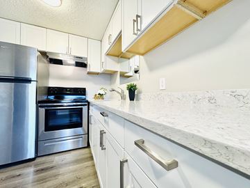 Tacoma apartment for rent - A kitchen with a stainless steel refrigerator and oven, white cabinets, and a marble countertop.