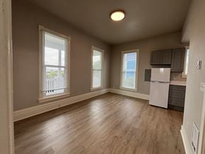 Tacoma apartment for rent - A spacious room with wooden floors and a white refrigerator.