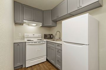 Seattle apartment for rent - A white refrigerator is in a kitchen with grey cabinets.