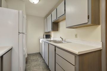 Seattle apartment for rent - A kitchen with white cabinets and a white fridge.