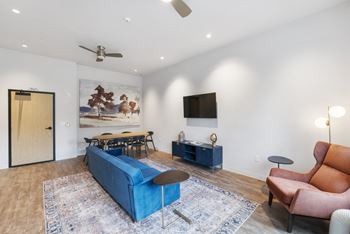 A living room with a blue couch, a brown chair, and a painting on the wall