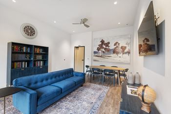 A living room with a blue couch, a bookshelf, and a painting on the wall