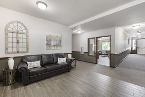 Olympia apartment for rent - A black leather couch sits in a spacious room with wood flooring and a large window.