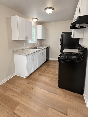 Lakewood apartment for rent - A kitchen with a black fridge and white cabinets.