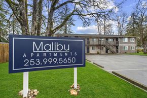 Lakewood apartment for rent - A blue sign for Malibu Apartments stands in front of a building.