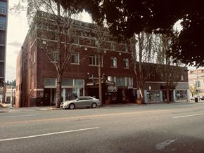 Olympia apartment for rent - A silver car is parked on the side of a street in front of a brick building.