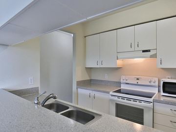 Seattle apartment for rent - a kitchen with a sink and stove and white cabinets