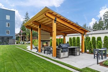 A wooden pergola with a grill and seating area