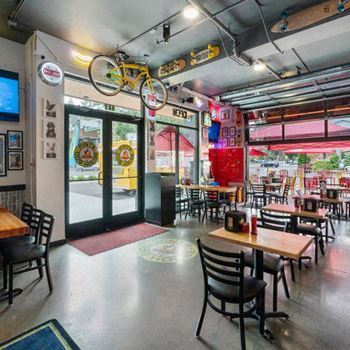 A restaurant with tables and chairs and a bicycle hanging from the ceiling
