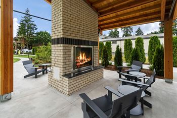 A modern outdoor patio with a fireplace and seating area