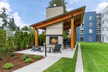 A modern outdoor patio with a fireplace and seating area