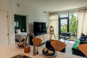 Washington apartment for rent - a kitchen with a sink next to a living room with a couch and a tv