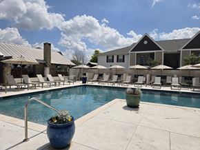 Bossier City apartment for rent - A pool area with a blue pot in the foreground and a building in the background.