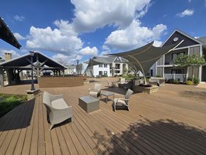 Bossier City apartment for rent - A wooden deck with chairs and tables is surrounded by buildings at Reserve of Bossier City Apartment Homes Bossier City, LA 71111