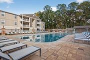 Ocean Springs apartment for rent - A large swimming pool surrounded by lounge chairs and a building in the background.