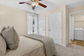 Ocean Springs apartment for rent - A bedroom with a bed, a ceiling fan, and a small refrigerator.