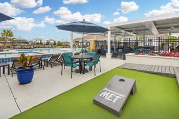A patio with tables and chairs and a pool with umbrellas
