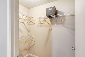 A white closet with a shelf and hangers