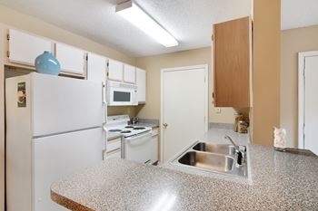 A kitchen with a granite countertop and white appliances