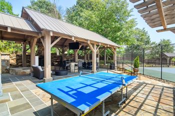 A blue table tennis table is in the middle of a patio