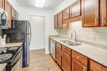 A kitchen with wooden cabinets and a black refrigerator and dishwasher