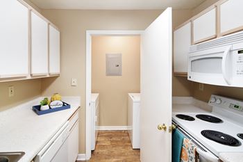 A kitchen with white appliances and white cabinets  and a door