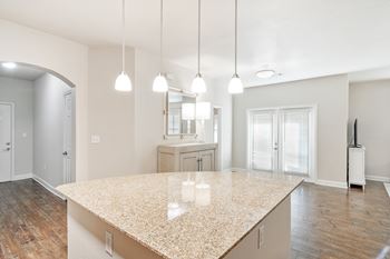 A kitchen with a granite countertop and pendant lights