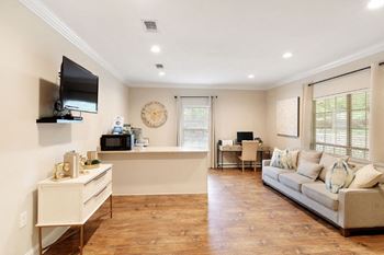 A living room with a couch and a desk in front of a window
