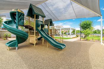 A playground with a green slide and a wooden structure 