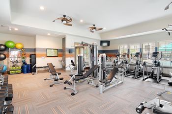 A gym with a variety of equipment including weights and cardio machines