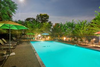 A swimming pool at night with umbrellas and chairs