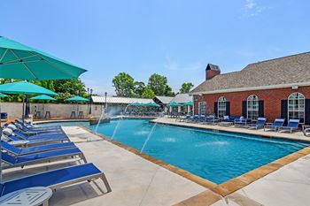 A pool with blue lounge chairs and umbrellas