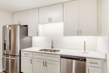 A kitchen with white cabinets and stainless steel appliances and dishwasher