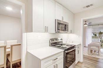 A kitchen with white cabinets and a stove top oven and microwave