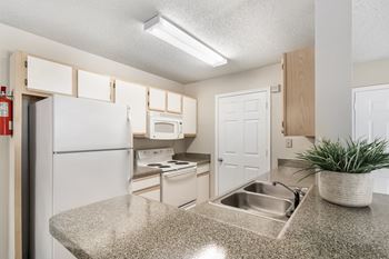 A kitchen with white appliances and a granite counter top