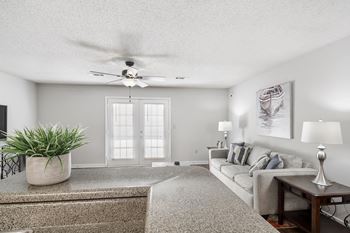A living room with a grey couch, a plant, and a painting on the wall