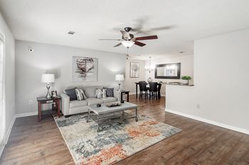 A living room with hardwood floors, a couch and a ceiling fan