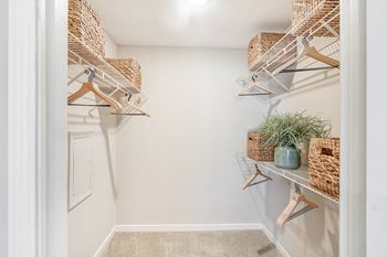 The walk in closet of a home with baskets and hangers on the wall