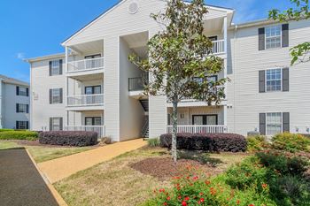 A white apartment building with a tree in front of it
