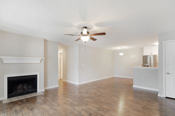 An empty living room with a ceiling fan and a fireplace 