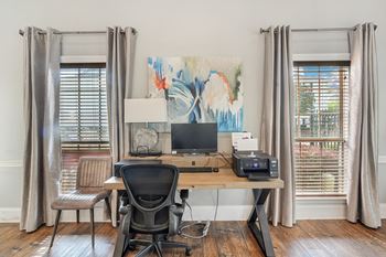 A home office with two windows and a desk with a computer
