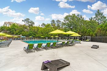 A swimming pool with green and yellow chairs and umbrellas