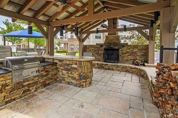 Grill entertaining area with a grill and a stone fireplace