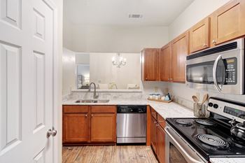 A kitchen with a stove, sink, and cabinets