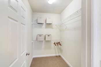 A walk in closet with shelves and a white door