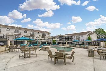 Outdoor lounge and grill patio with grass and tables and chairs at ashford place apartment homes in flowood mississippi
