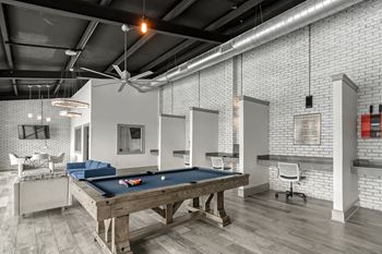 A pool table in a living room with white brick walls