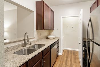A kitchen with a sink, refrigerator, and cabinets