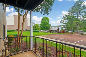 A view from a balcony looking out at a parking lot and trees